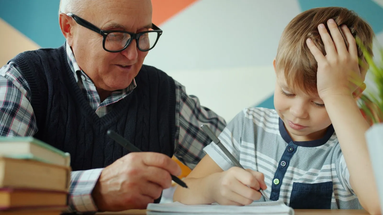 Senior man assisting young boy with homework, emphasizing family and education.